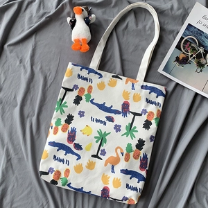 Close-up of a white canvas tote bag with vibrant Hawaii flamingo and pineapple prints