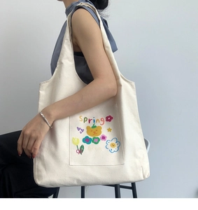 Detailed close-up of a cream canvas tote bag featuring an orange bear and tulip print