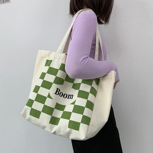 Detail of canvas tote bag showing green checkerboard pattern and Boom letter print