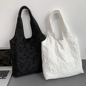 Détail macro de la texture brodée rose 3D sur les sacs cabas en jacquard noir et blanc