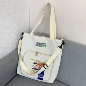 Detailansicht der beigen Nylon-Einkaufstasche mit modischen Aufnähern und Gurtband