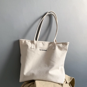 Detail view of off-white canvas tote bag with black by morisot text and dual handles