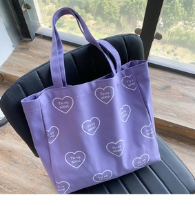 Détail du cabas en toile violette avec motifs de cœurs blancs et texte en français
