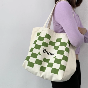 Detail of canvas tote bag with green checkerboard pattern and black Boom text print