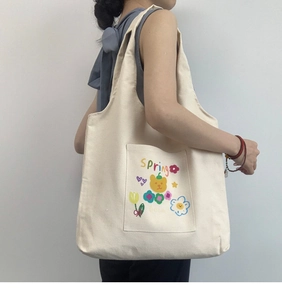 Detail of a cream canvas tote bag with cute spring cartoon bear and tulip print