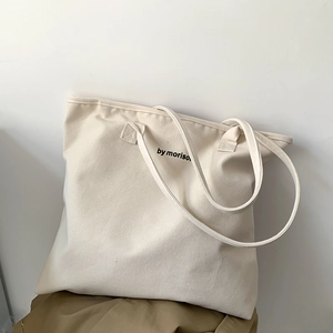Detail of a minimalist off-white canvas tote bag featuring black by morison lettering
