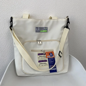 Detail der cremeweißen Nylontasche mit Industrie-Patches und Reißverschlusstasche