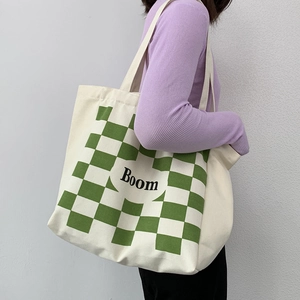 Detail of canvas tote bag featuring green checkerboard pattern and Boom letter print