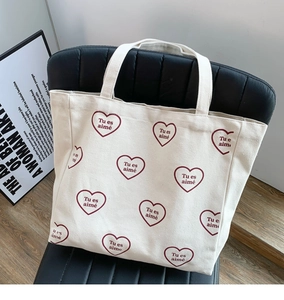 Détail du sac cabas en toile avec motifs cœurs rouges et texte français sur une chaise