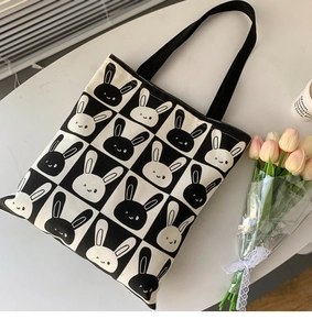 Detail of canvas tote bag featuring cute rabbit checkerboard print with black shoulder straps