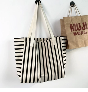 Detail of striped canvas tote bag showing thick fabric texture and metal snap closure