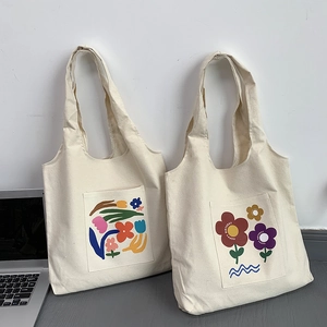 Detail of white canvas tote bags with colorful floral prints and Happy Birthday text
