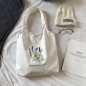 Flat lay of white canvas tote bag with purple lavender print and cotton texture