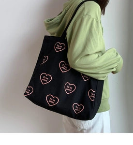 Détail d'un sac cabas en toile noire avec motifs cœurs roses et lettrage imprimé français