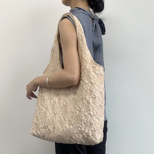 Gros plan détaillé sur la texture florale en relief du sac cabas en toile beige abricot