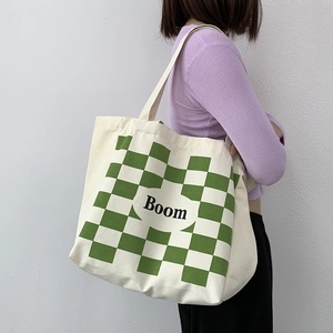 Detail of large canvas tote bag showing green checkerboard pattern and Boom lettering