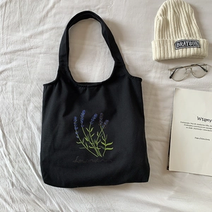 Detailed embroidery of purple lavender and text on a black canvas tote bag for students