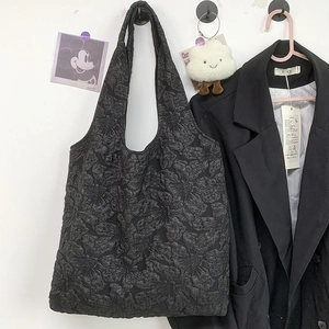 Détail du sac cabas noir montrant la texture jacquard florale 3D et le motif gaufré