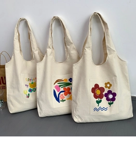 Detailed view of white canvas tote bags with floral and bear prints on front pockets