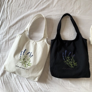 Detailed close-up of lavender embroidery on high-quality white and black canvas tote bags