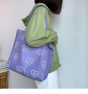 Détail du sac cabas en toile mauve avec motifs cœurs blancs et texte Tu es aimé