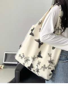 Close-up of white canvas tote bag with black butterfly embroidery and lace mesh