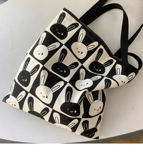 Close-up of checkered canvas tote bag with cartoon rabbit prints and black handles