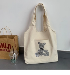 Close-up of off-white canvas tote bag featuring a cute houndstooth bear pattern pocket