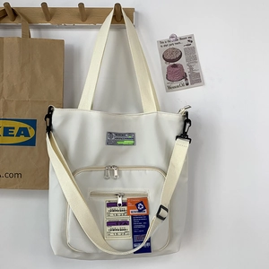 Detail der weißen Nylon-Tragetasche mit Luftfahrt-Patches und verstellbarem Schultergurt