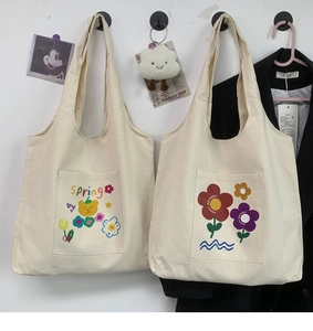 Detail of cream canvas tote bags with cartoon bear and floral prints in a home setting