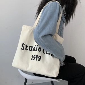Detail view of the embroidered canvas tote bag showing the Studio Clip 1949 typography