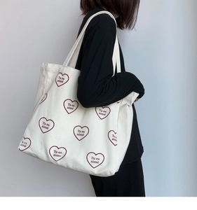 Détail du motif cœur et du texte Tu es aimé sur le sac cabas en toile beige