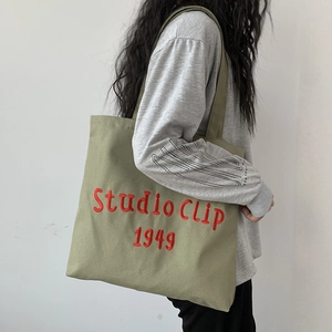 Detail view of army green canvas tote with red Studio Clip 1949 embroidery lettering