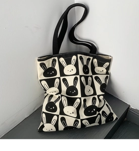 Detail of cute rabbit pattern on black and white checkered canvas tote bag with strap