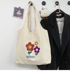 Close-up of cream canvas tote bag featuring floral print and front pocket detail