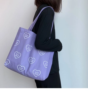 Détail du sac cabas en toile violette avec motifs de cœurs blancs sur l'épaule