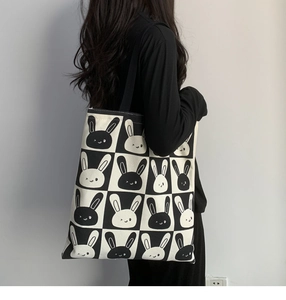 Detailed view of the checkered canvas tote bag with a cartoon rabbit print worn by a model