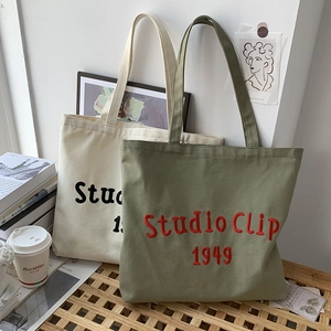 Detail of embroidered canvas tote bags in off-white and olive green colors