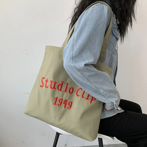 Detail of red Studio Clip embroidery on olive green canvas tote bag with textured fabric