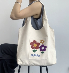 Minimalist beige canvas tote bag with floral print worn on shoulder for daily travel