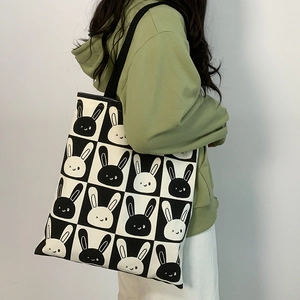 Checkerboard canvas tote bag with cute cartoon rabbit patterns shown on a model's shoulder