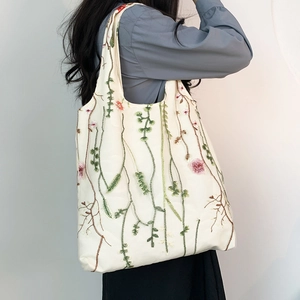 Detailed view of floral embroidery on a white canvas tote bag with plant vine patterns