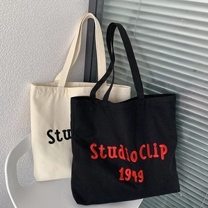 Detailed close-up of thick canvas tote bags with Studio CLIP 1949 embroidery on chairs