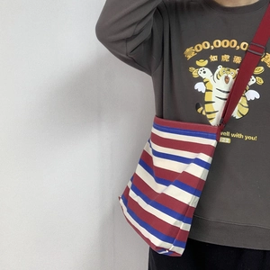 Detail of red white and blue striped canvas crossbody bag with red adjustable strap