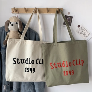 Detailed embroidery on canvas tote bags in cream and olive green with dual straps
