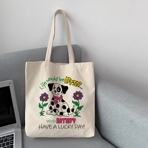 Sac cabas en toile avec illustration de dalmatien et fleurs posé sur un canapé gris