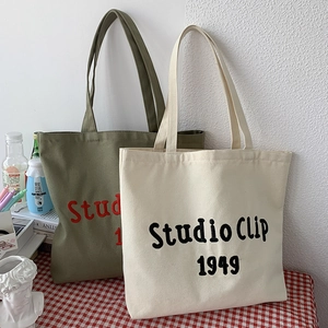 Detail of Studio Clip 1949 embroidered canvas tote bags on a red checkered tablecloth
