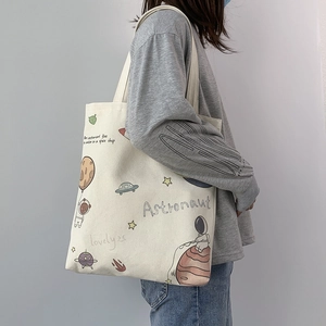 Detail of canvas tote bag with astronaut illustration on shoulder of a model