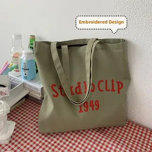 Detailed red Studio Clip 1949 embroidery on green canvas tote bag with studio setting
