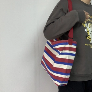 Close-up of red, white, and blue striped canvas bag with a sturdy red shoulder strap